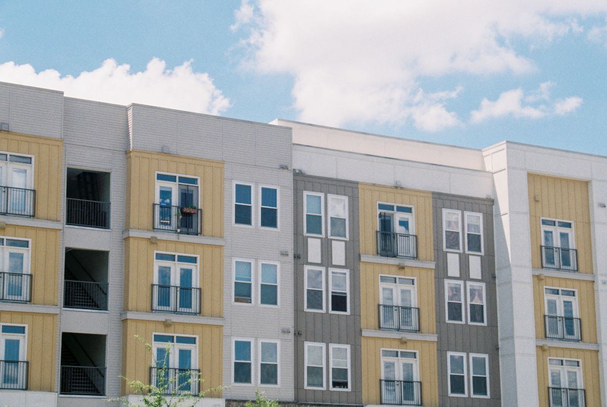 A bright, four-storey apartment building with balconies under a blue sky