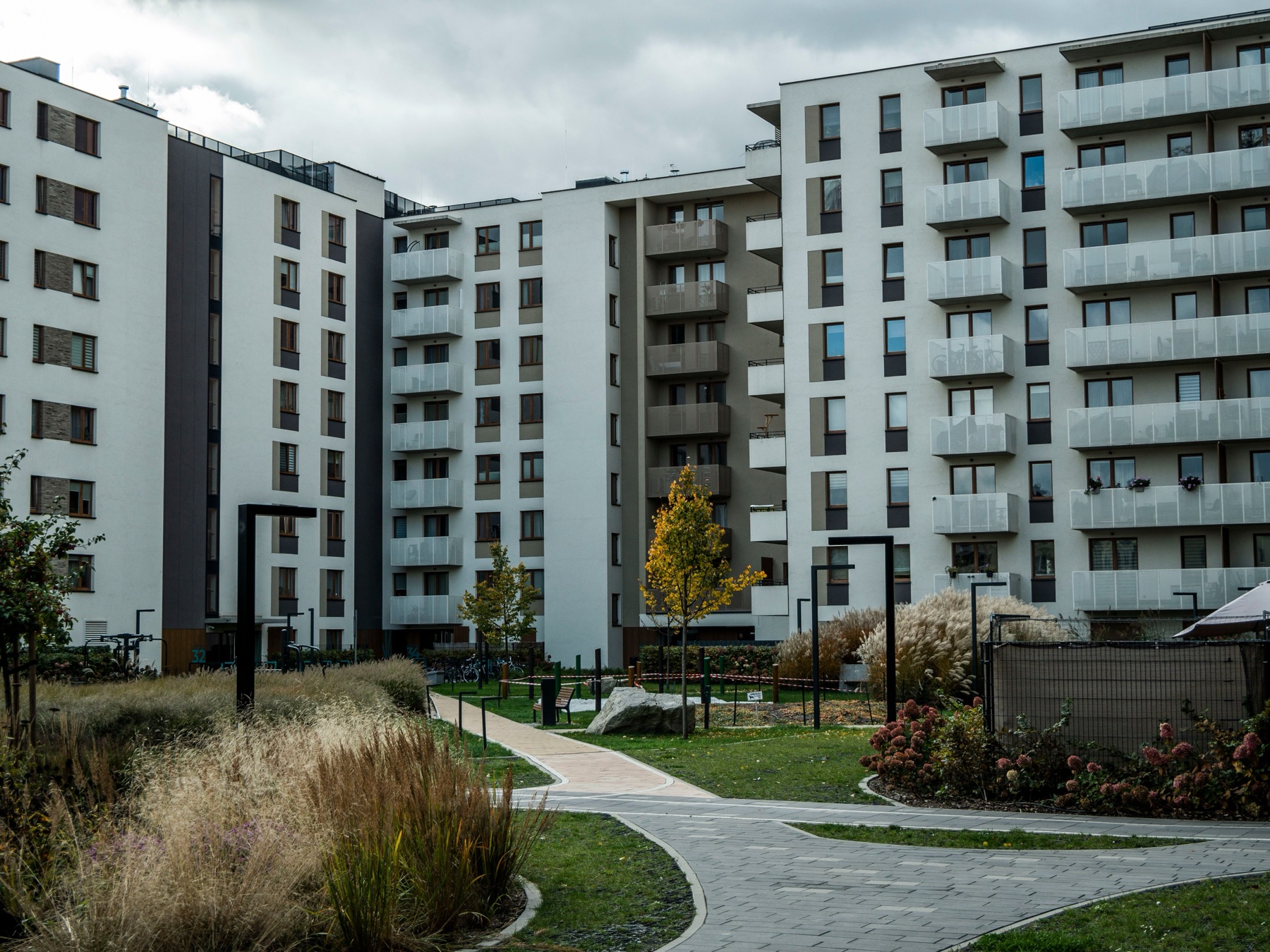 A multifamily apartment courtyard with landscaped walkways, ornamental grasses, and a footpath between residential towers