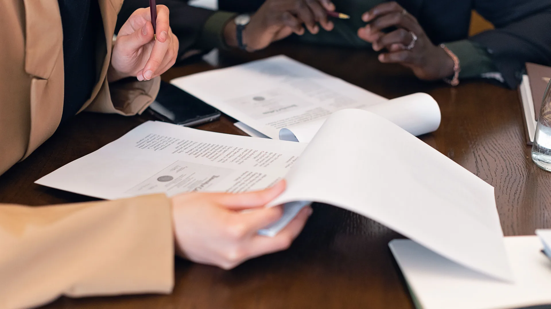 Two people at a desk working through the written terms of an agreement, pages turned mid-review